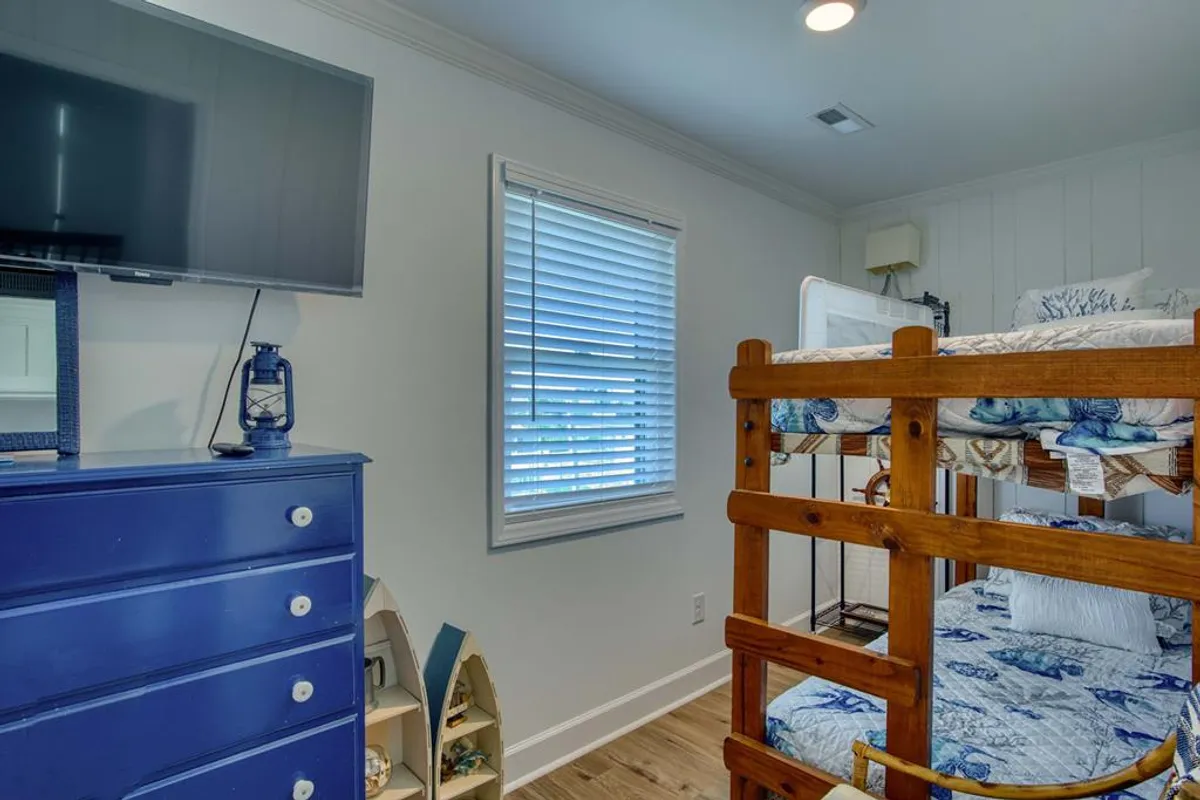 A playful yet comfortable kids’ bunkroom featuring a sturdy bunk bed, a cheerful blue dresser, and a wall-mounted TV. The room exudes warmth and fun, making it ideal for bedtime stories, movie nights, or play. The space is clearly designed to foster both rest and imagination for younger guests.